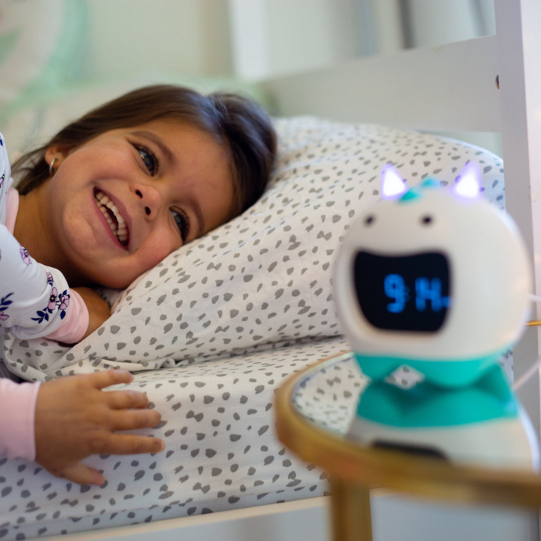 Child in bed with a NESSI clock on a nightstand displaying 9:14.