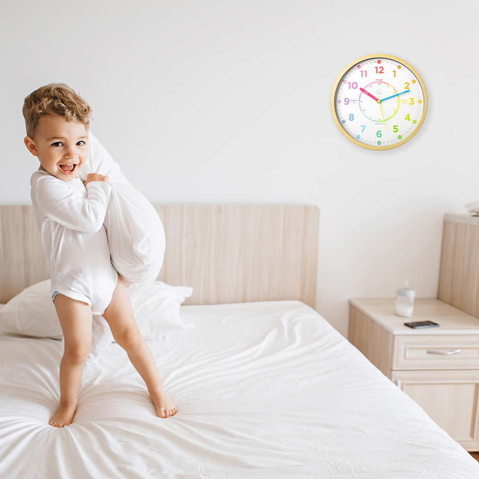 Child playing on a bed with a clock on the wall in the background